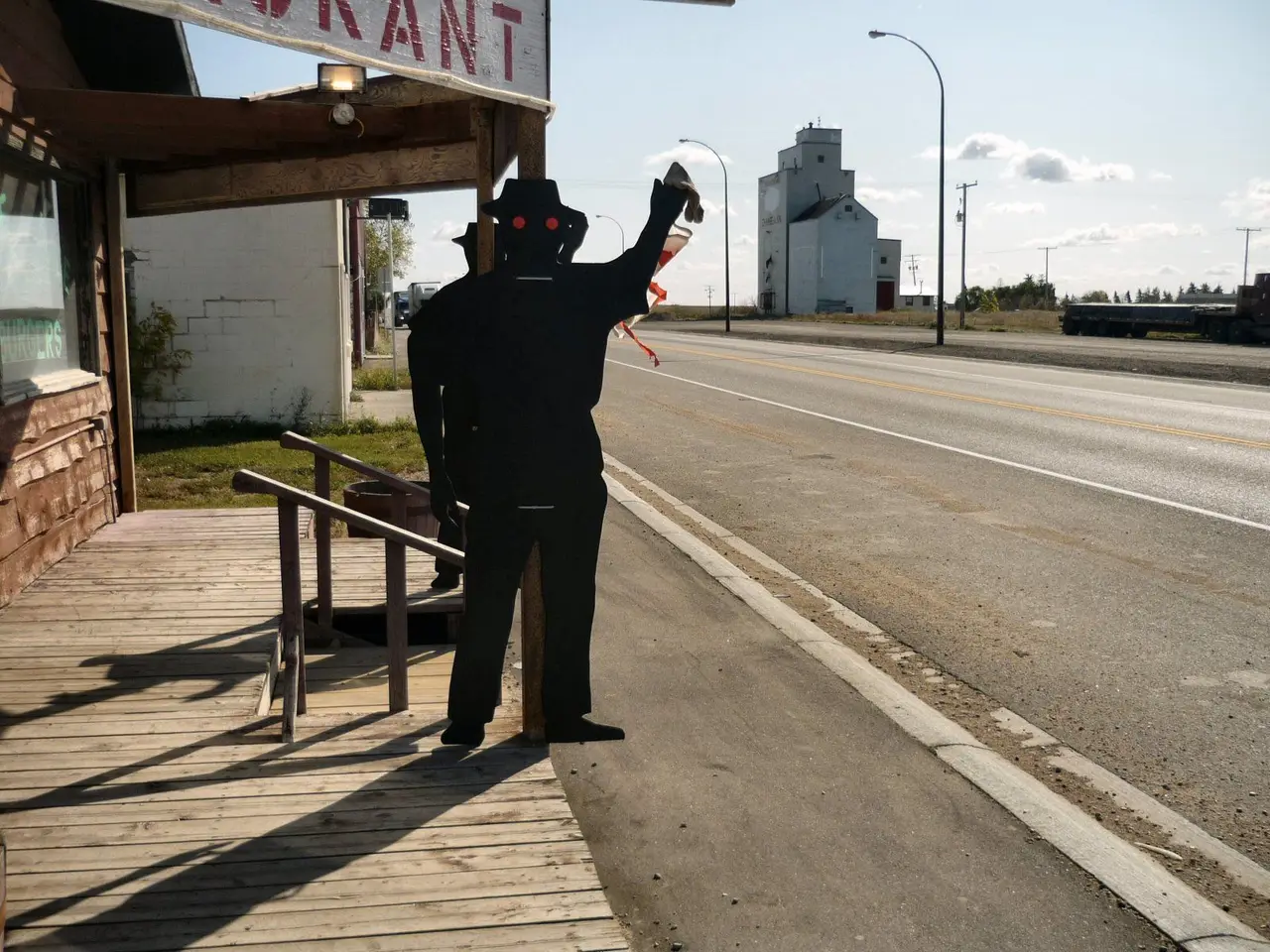 Plywood figure outside the restaurant, with grain elevator on Highway 11, 2008